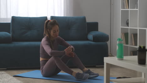 slender-sporty-woman-is-sitting-on-floor-looking-at-fitness-tracker-gadget-for-healthy-lifestyle-home-training-and-wellness-concept